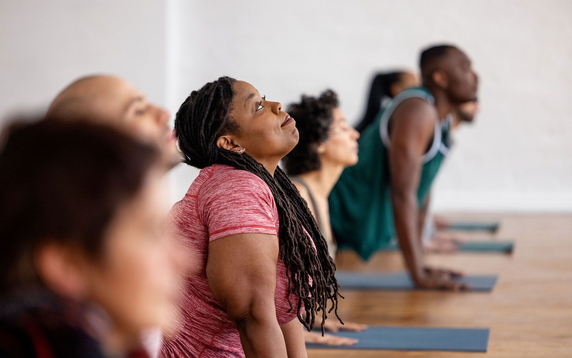 A group of people are doing yoga together in a gym.