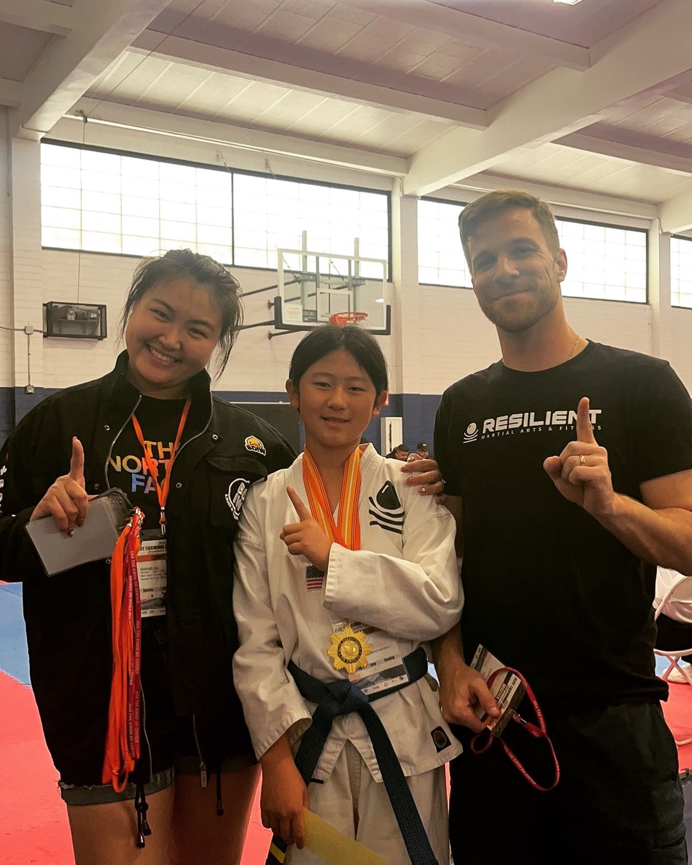 A man and two girls are practicing karate in a gym.