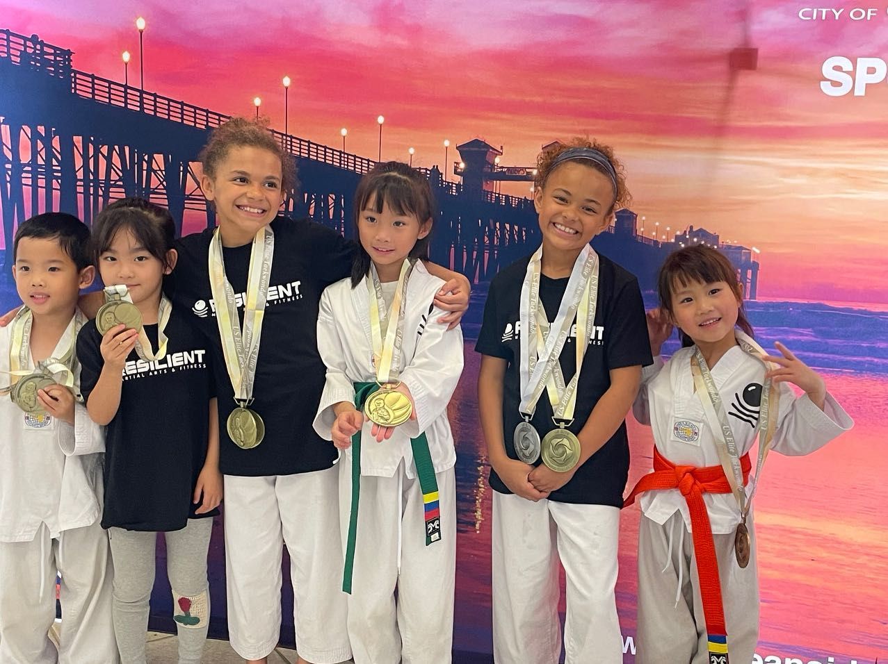 A group of children posing for a picture with medals around their necks