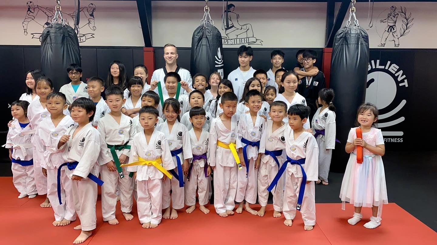 A group of children in karate uniforms are posing for a picture in a gym.