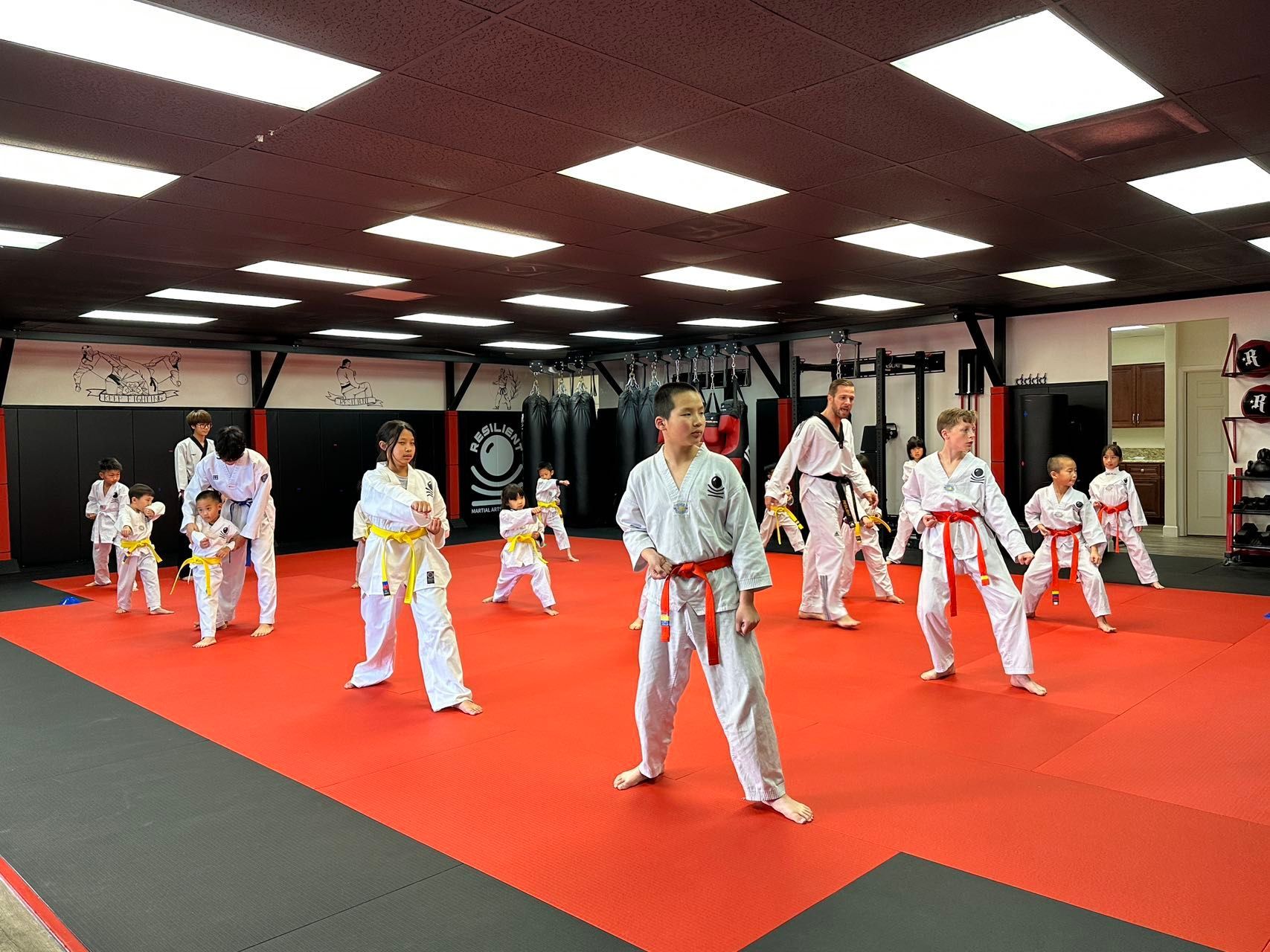 A group of children are practicing martial arts in a gym.