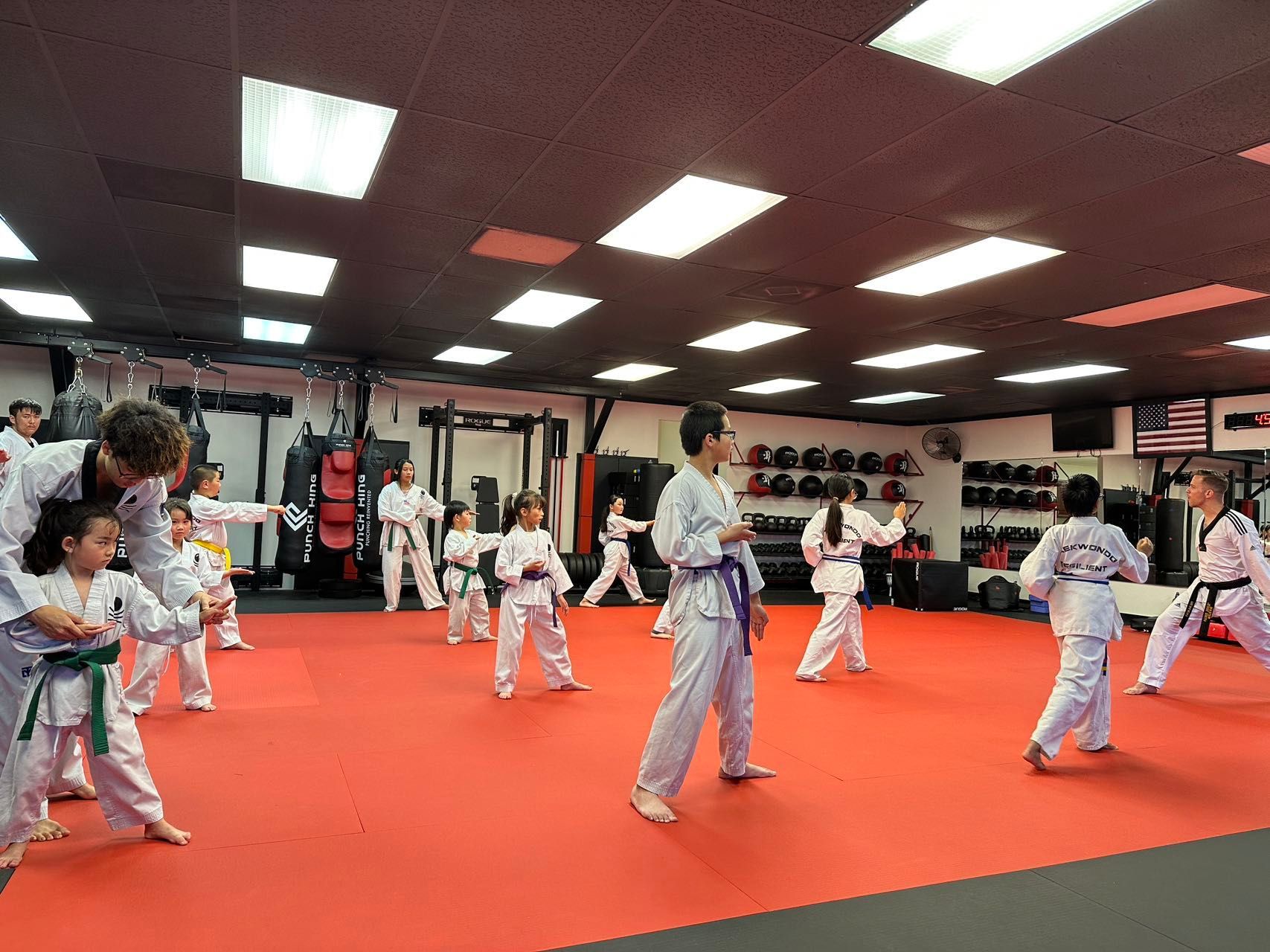 A group of children are practicing martial arts in a gym.