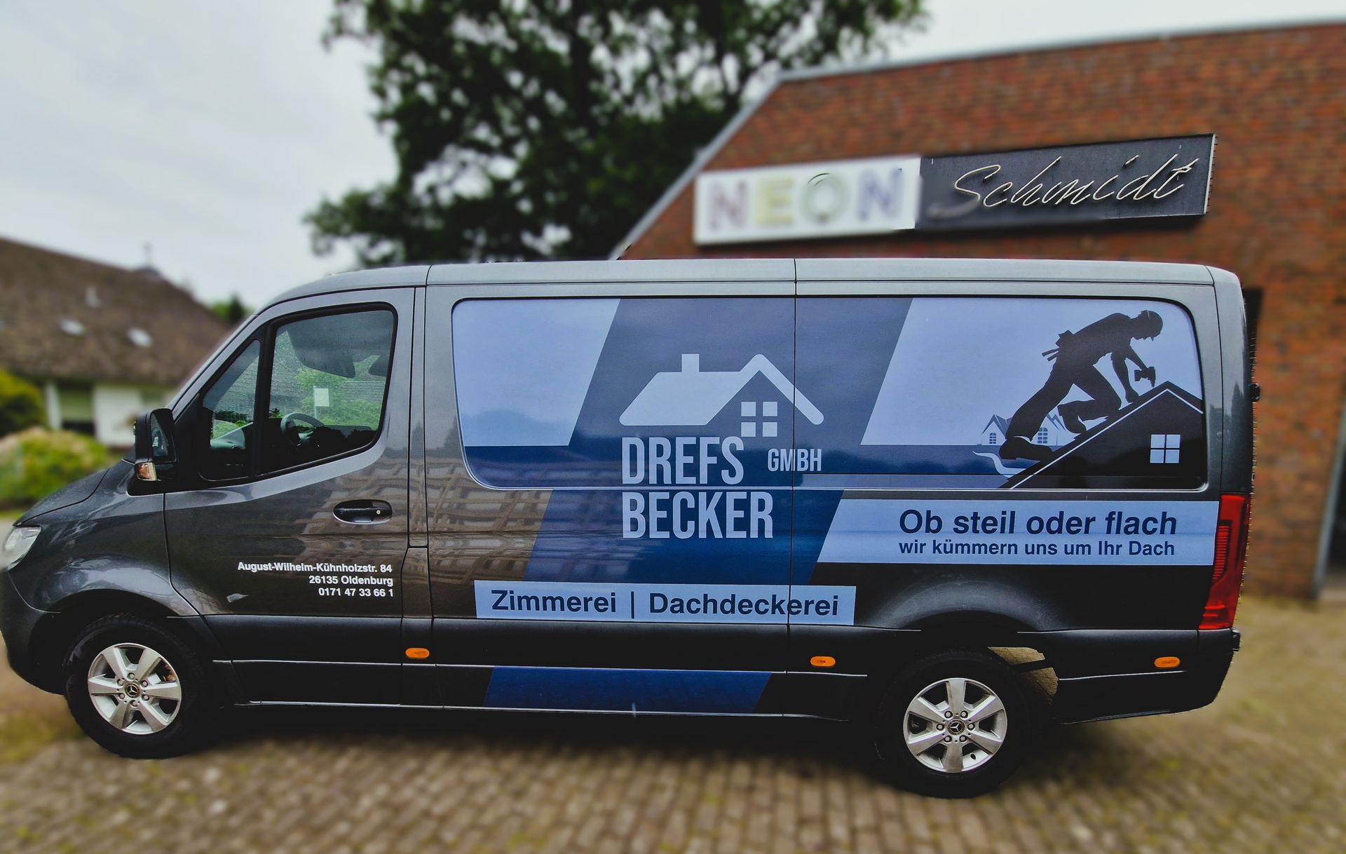 Dunkler Transporter mit Dachgrafik und „DREES & BECKER“-Schriftzug; vor einem Gebäude geparkt.
