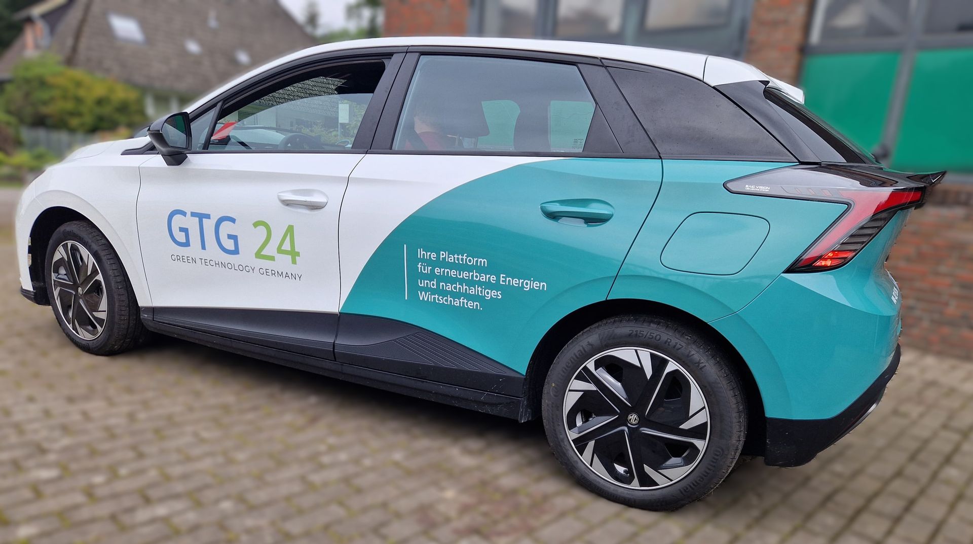 Weiß-blaugrünes MG-Auto mit „GTG 24“-Logo im Freien geparkt.
