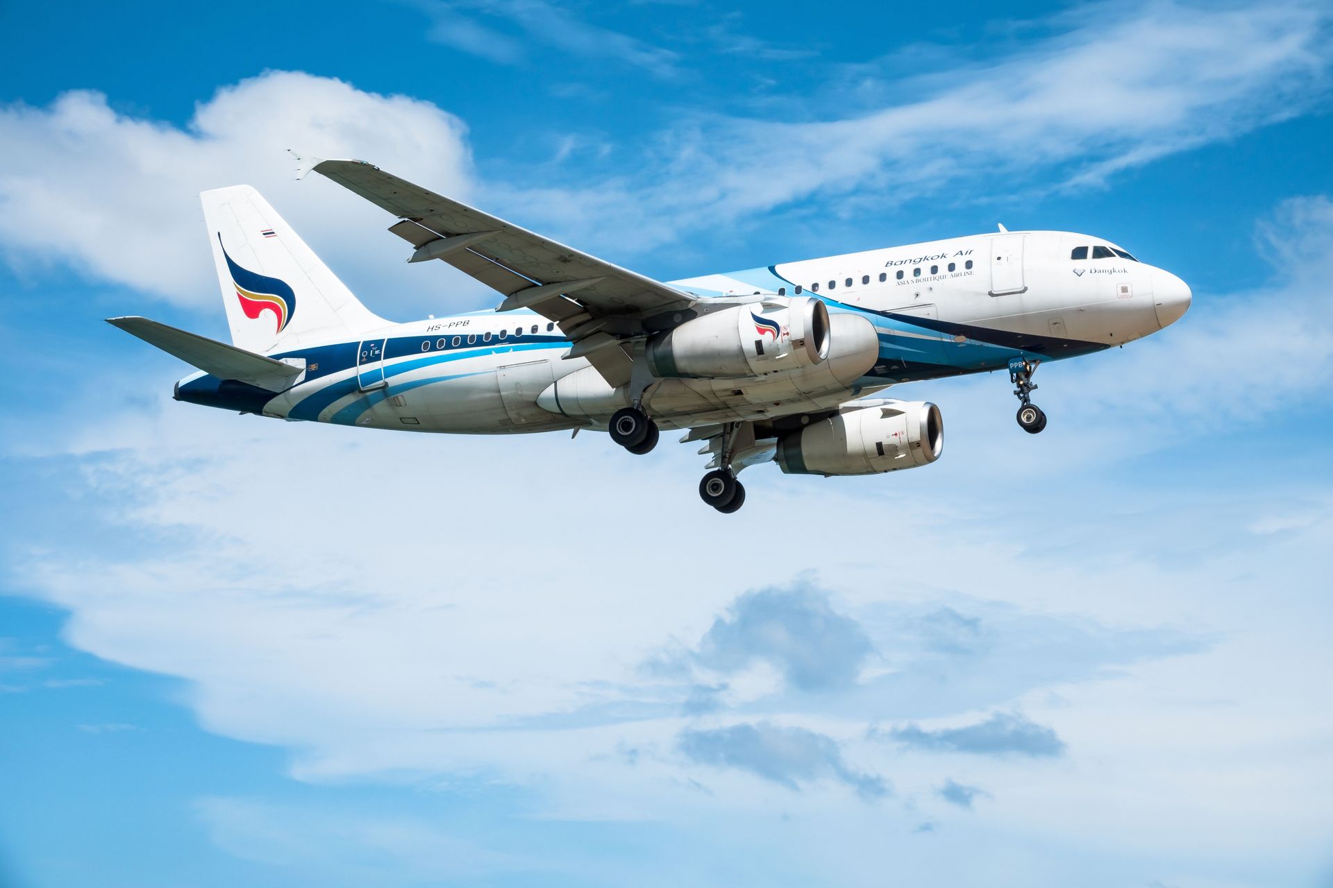 White and blue passenger jet descending against a clear blue sky