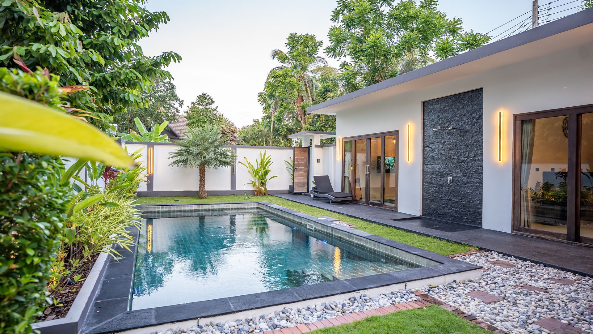 Modern house with a private backyard pool, white walls, greenery, and sliding glass doors