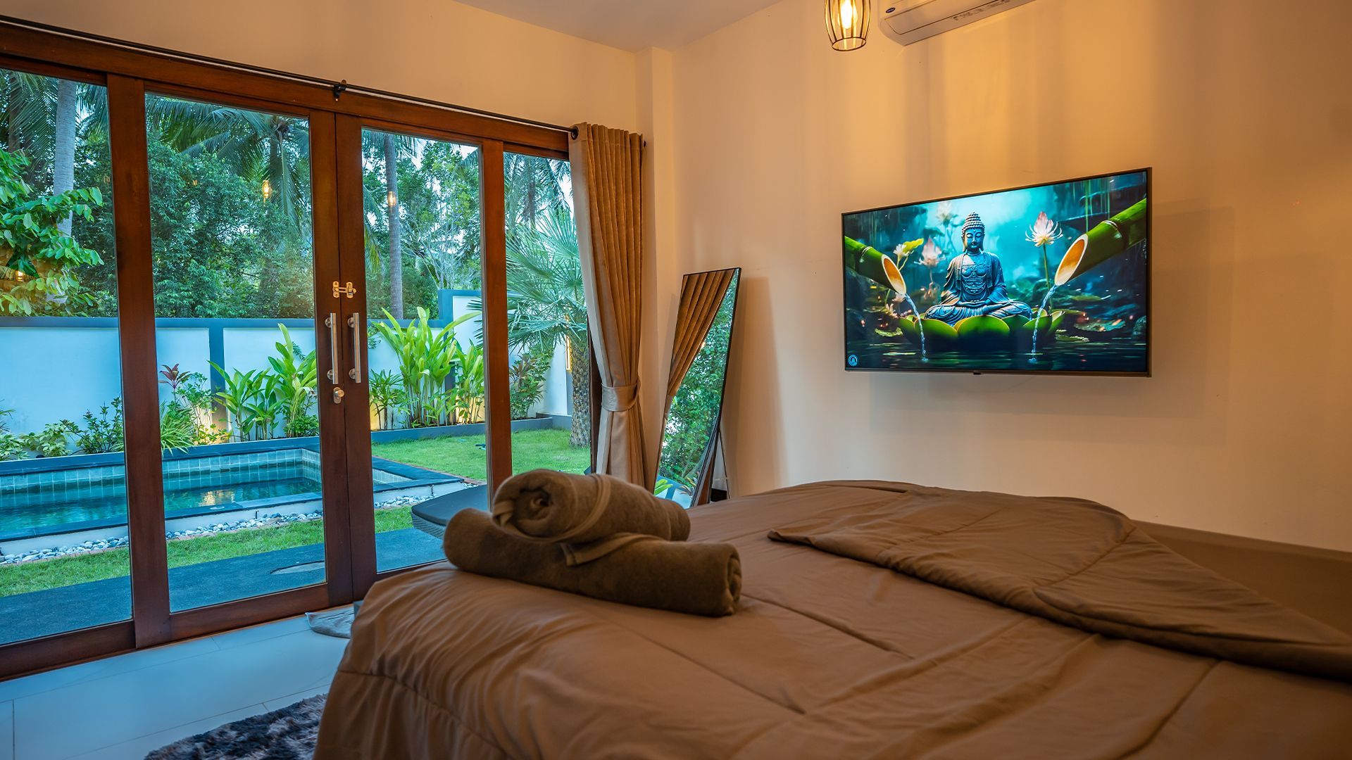 Bedroom with large sliding glass doors overlooking a lush garden and a wall-mounted TV above the bed.