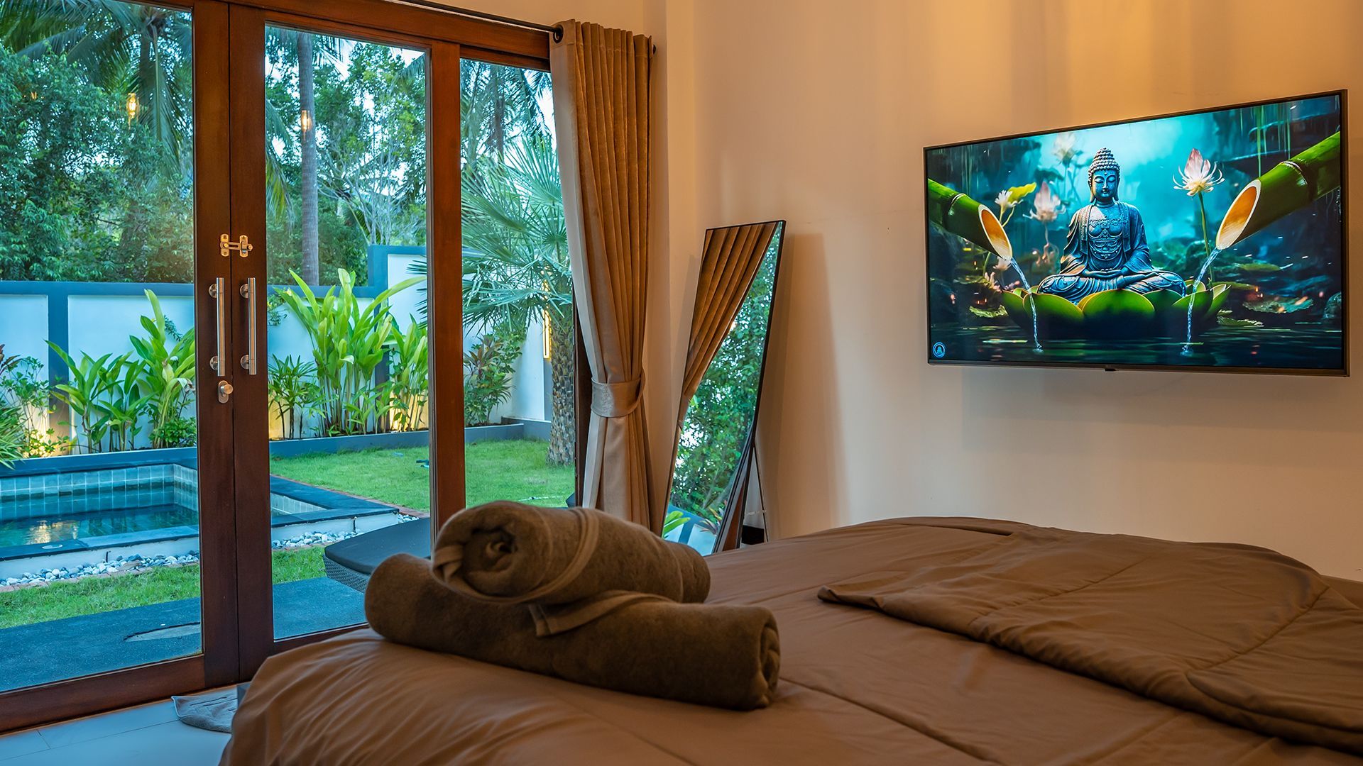 Cozy bedroom with a bed, tropical view through glass doors, and a wall-mounted TV showing an aquarium scene
