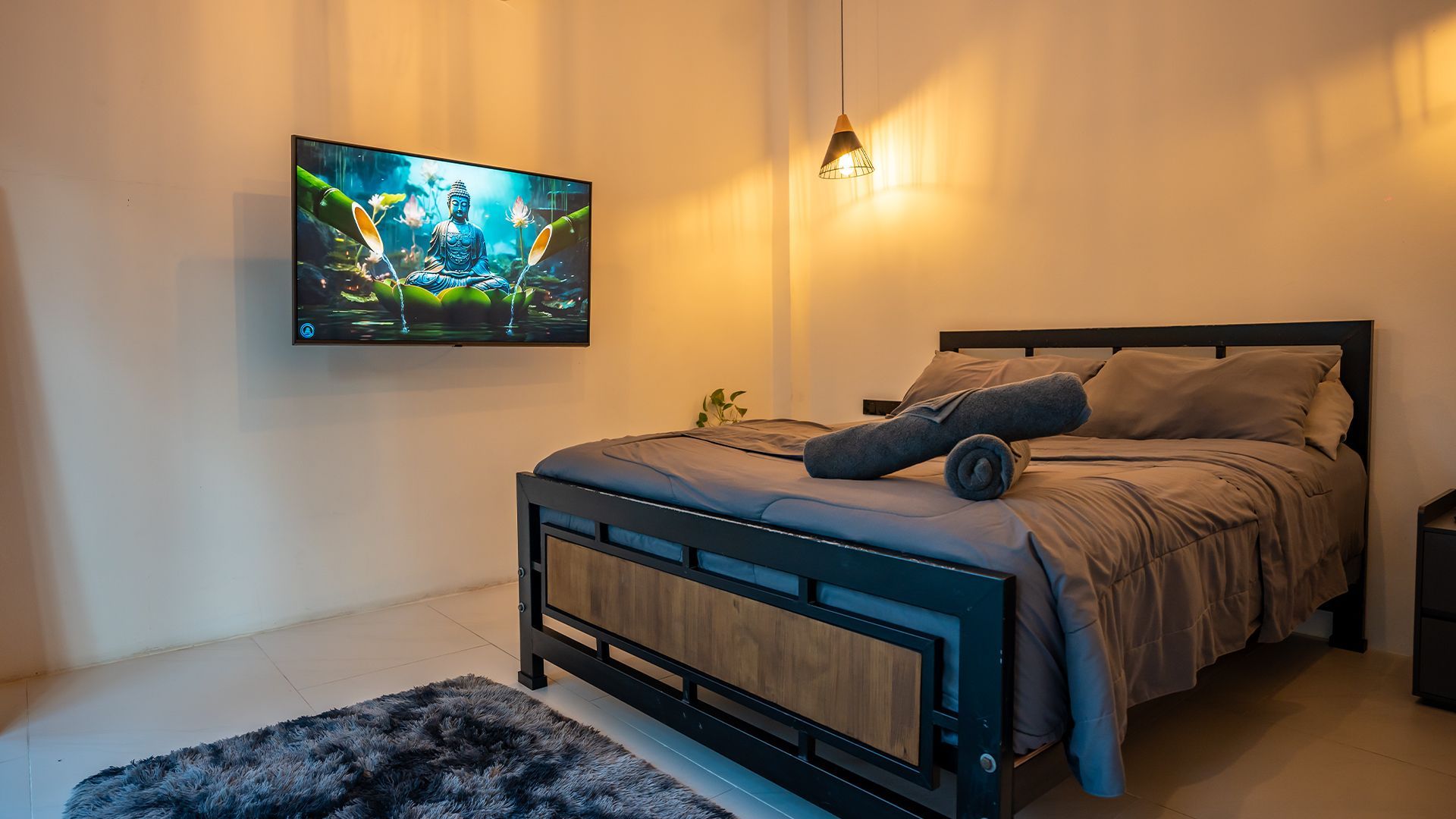 Cozy bedroom with wall-mounted TV, bed, and warm lighting