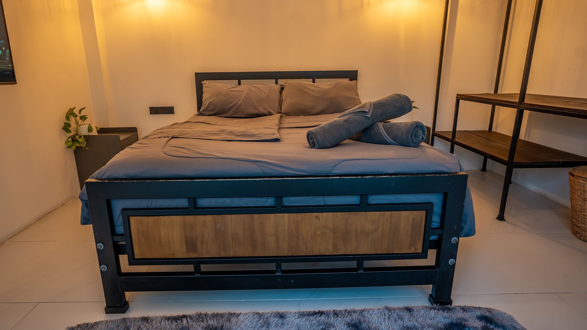 Modern bedroom with a blue upholstered bed, warm lighting, and a person lying across it.