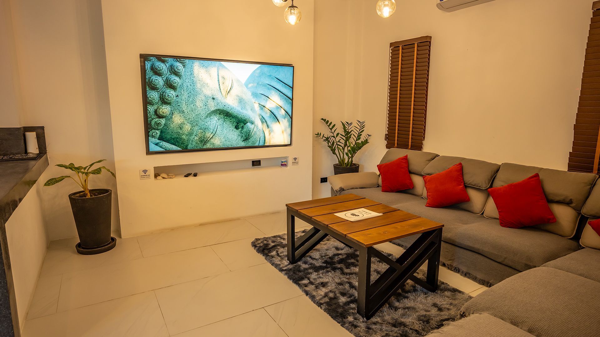 Modern living room with gray sectional, wall-mounted TV, coffee table, and warm lighting