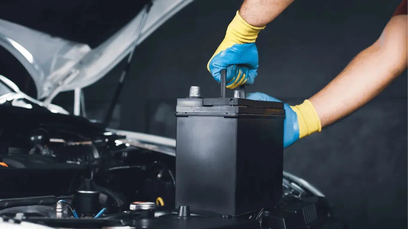 Mechanic installing new car battery under the hood