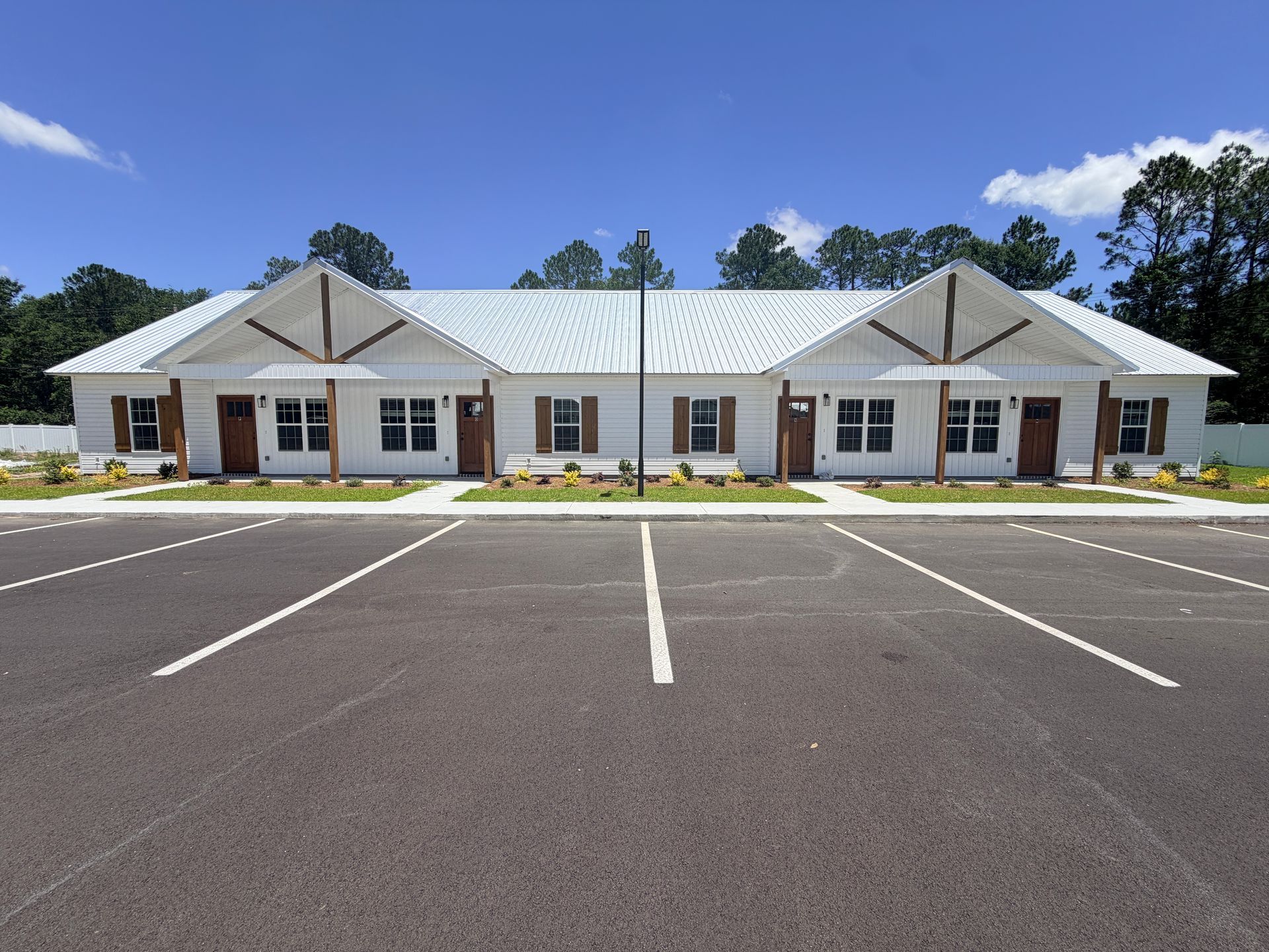 Single-story white office building with parking lot and clear blue sky