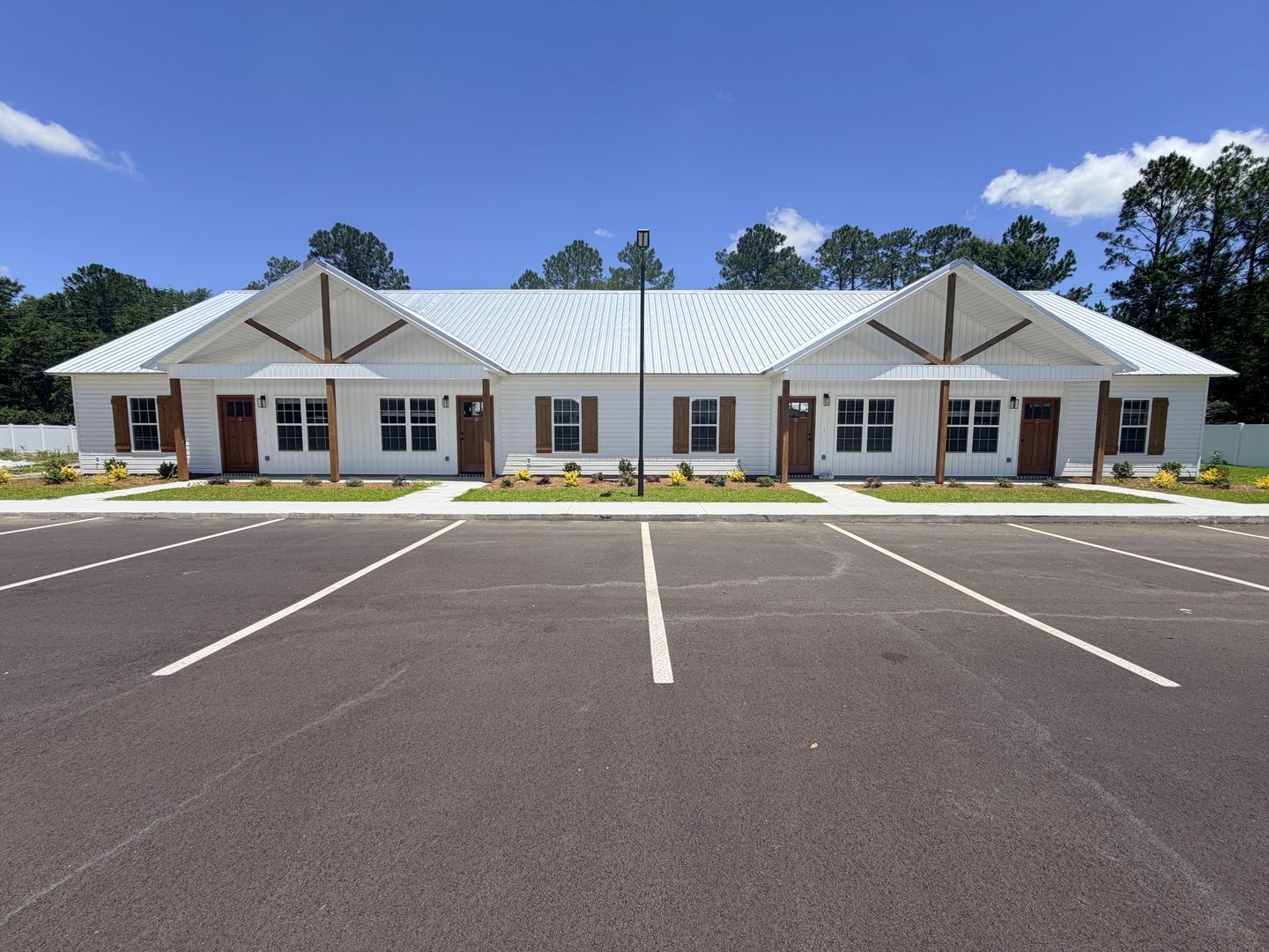 Single-story brick office building with white roof and empty parking lot under a clear blue sky