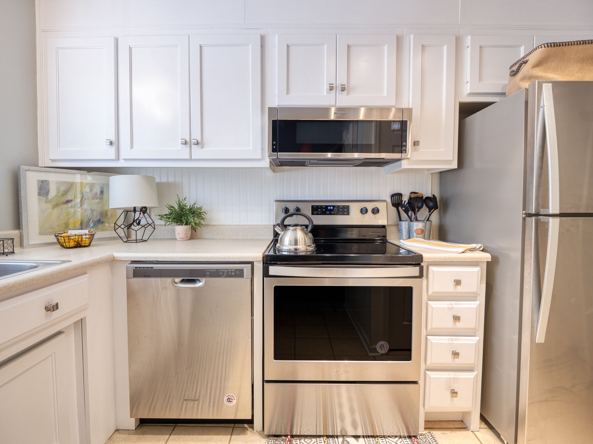 Bright modern kitchen with white cabinets, stainless steel appliances, and a silver refrigerator