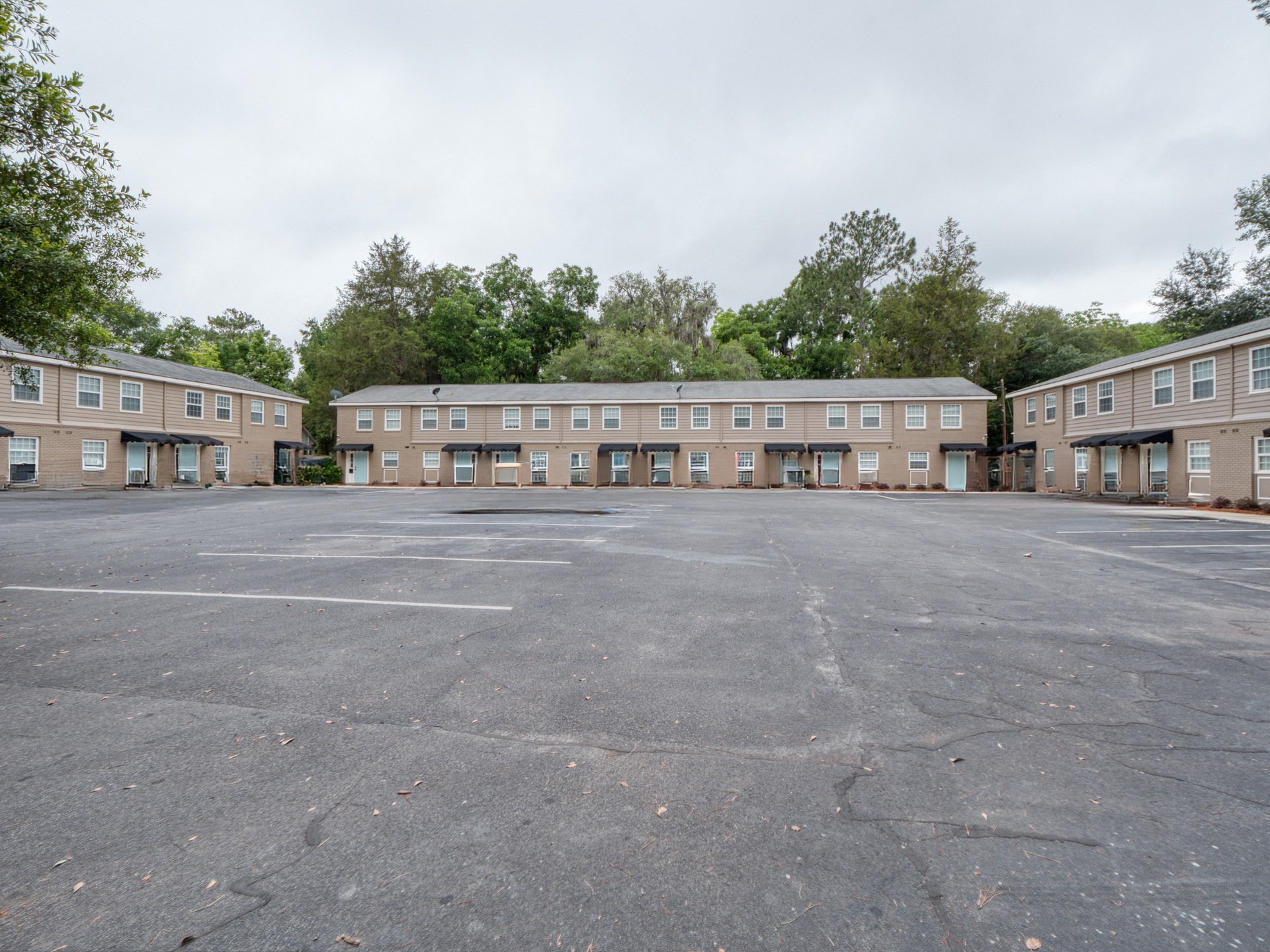 Empty parking lot in front of beige apartment buildings under a cloudy sky