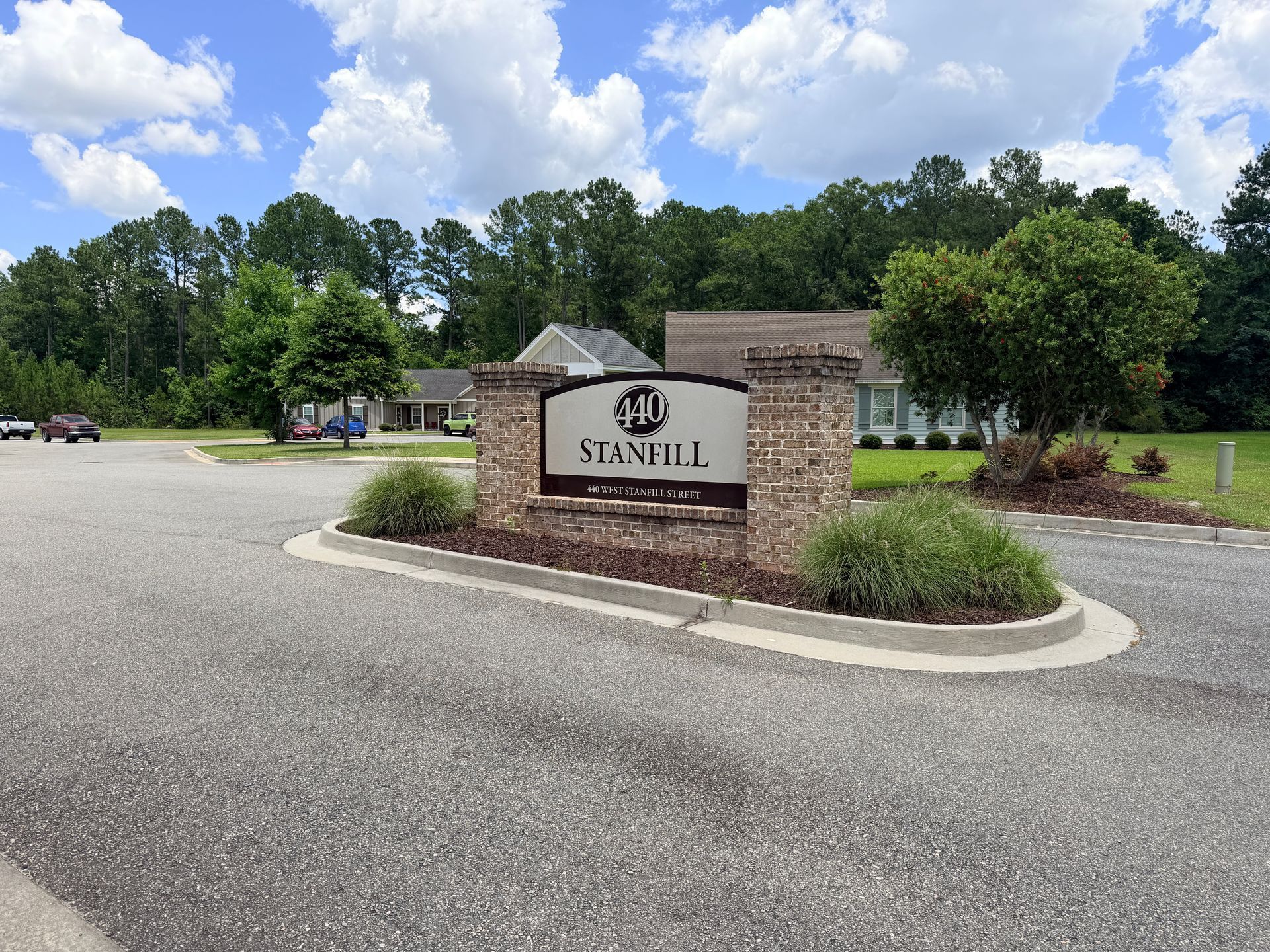 Stone entrance sign reading “STANFILL” at a landscaped residential community under a partly cloudy sky