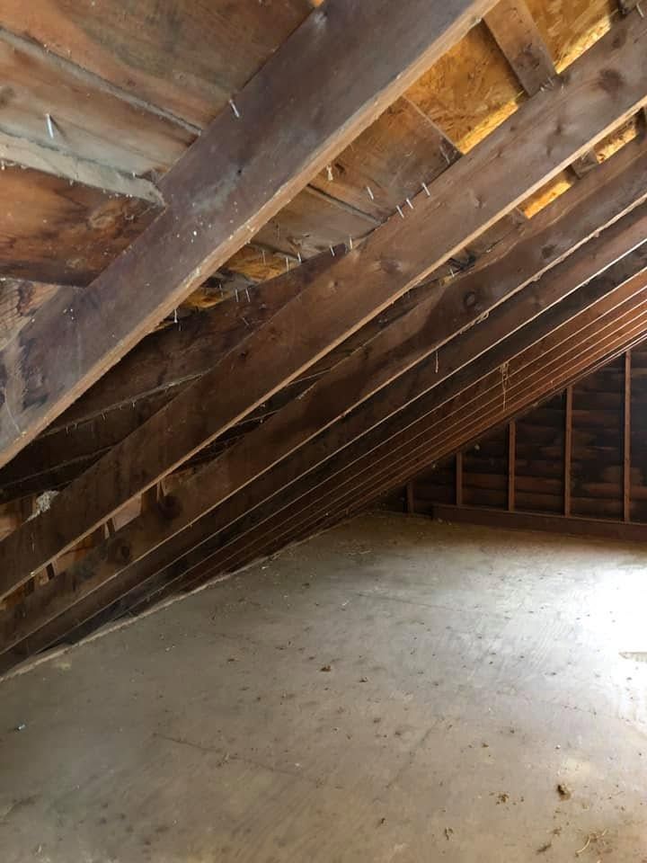 Empty attic with exposed wooden rafters and a bare floor under slanted roof beams. Empty attic with exposed wooden rafters and a bare floor under slanted roof beams.