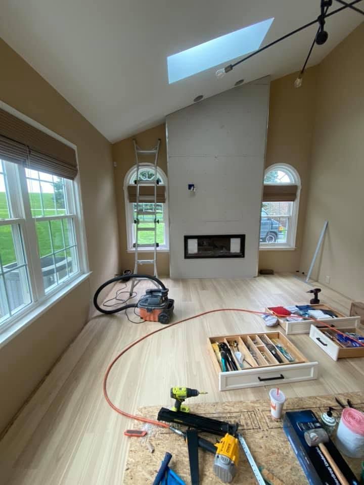 Renovation room with skylight, large windows, fireplace, tools, and construction materials on the floor
