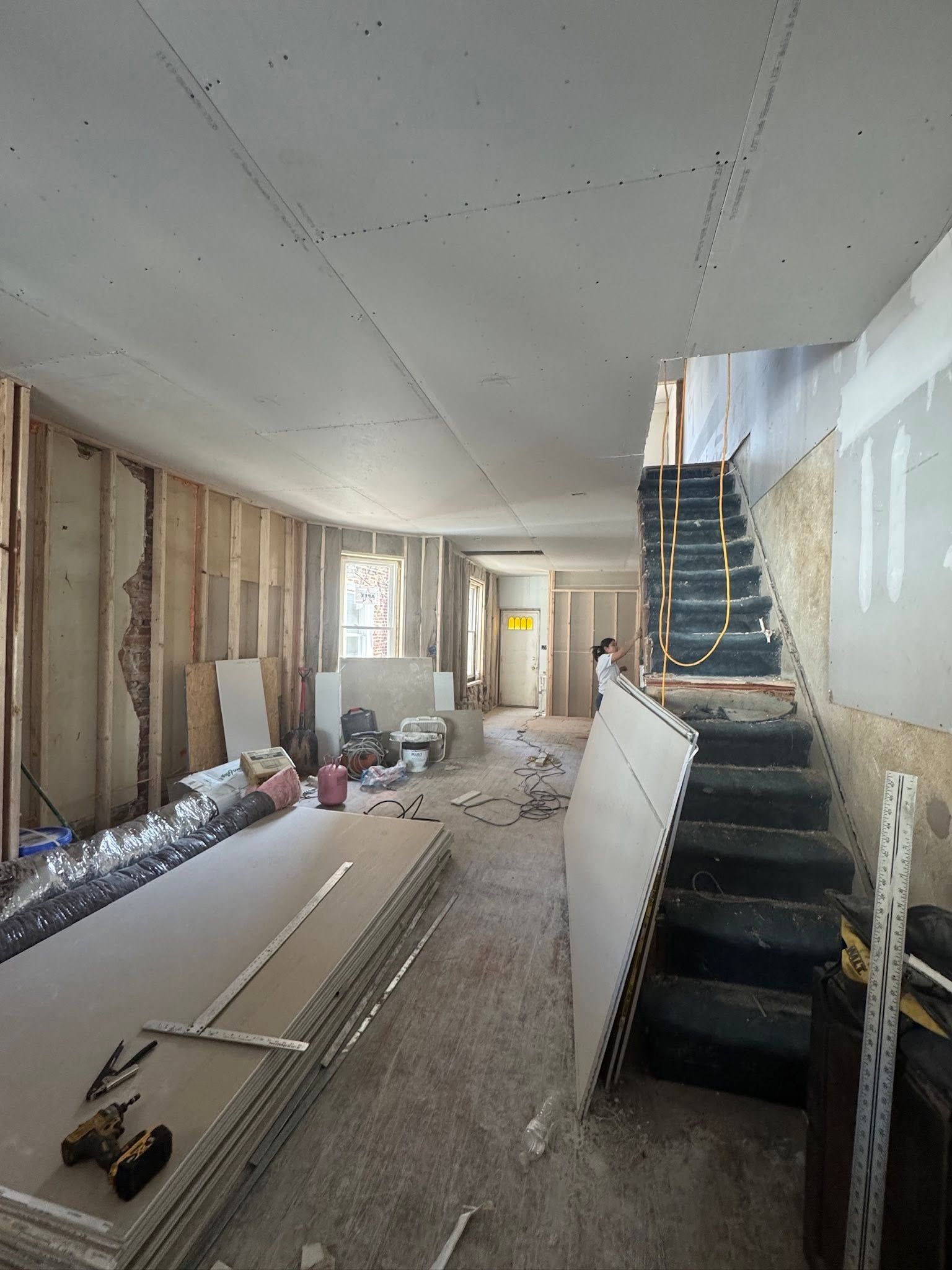 Renovation site with exposed walls, scattered tools, and a staircase under construction. Renovation site with exposed walls, scattered tools, and a staircase under construction.