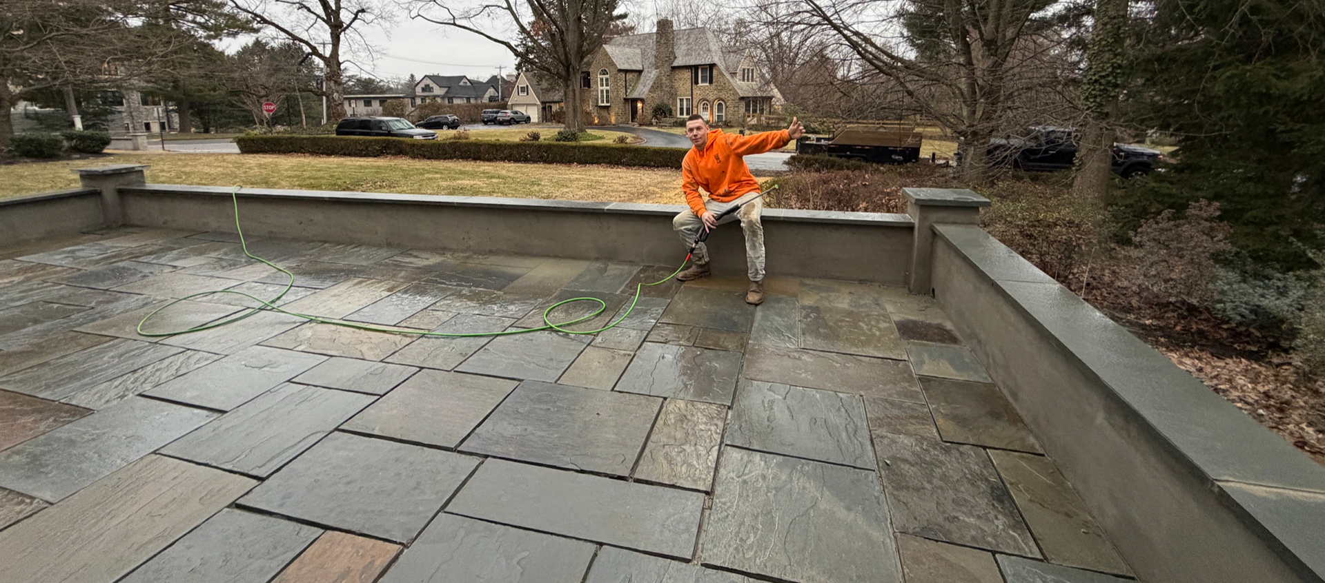 Freshly paved concrete driveway beside a house, with trees, a blue umbrella, and a small orange machine nearby