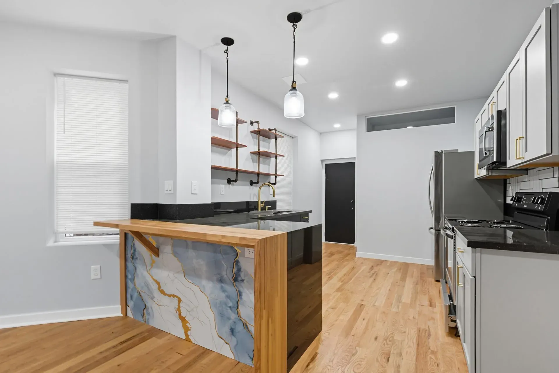 Modern kitchen with island, wood floors, pendant lights, stainless appliances, and gray cabinetry Modern kitchen with island, wood floors, pendant lights, stainless appliances, and gray cabinetry