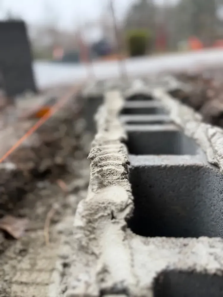 Close-up of stacked cinder blocks with wet mortar on a construction site, shallow depth of field