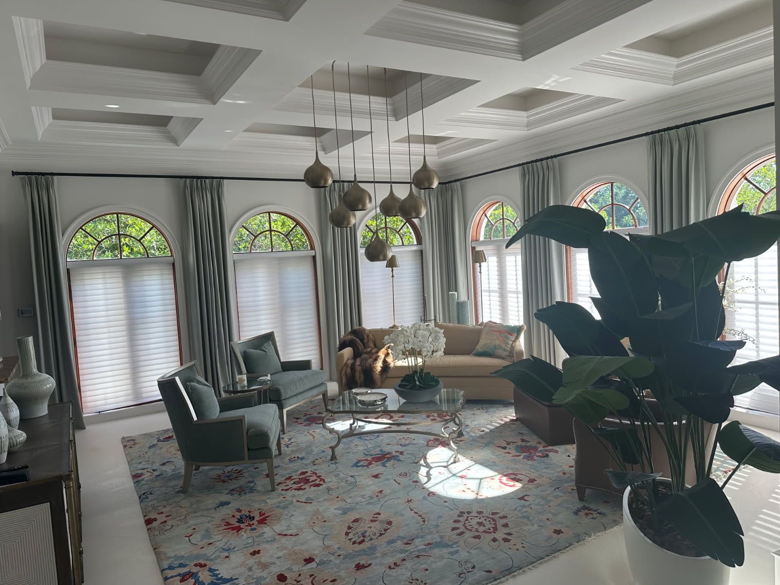Living room with arched windows, light blue armchairs, and a patterned rug.