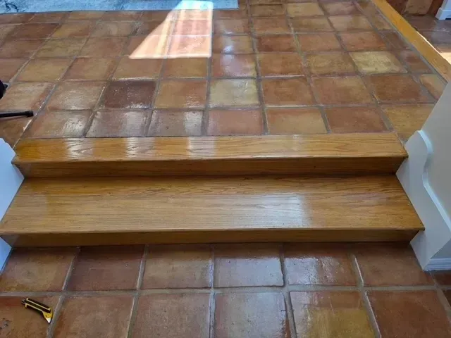 Wooden steps leading up, set on brown tiled flooring.