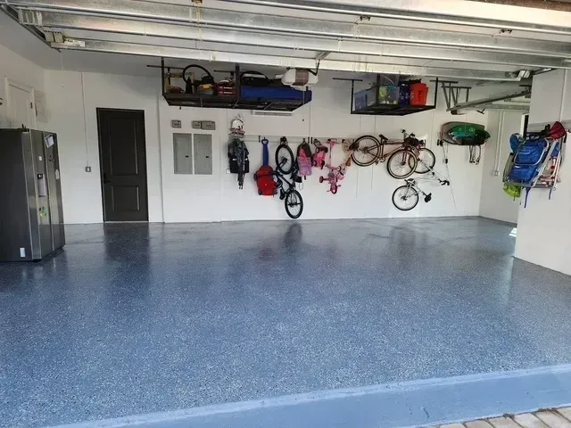 Garage with blue speckled epoxy floor, storage racks, bikes, and various items hanging on the wall.