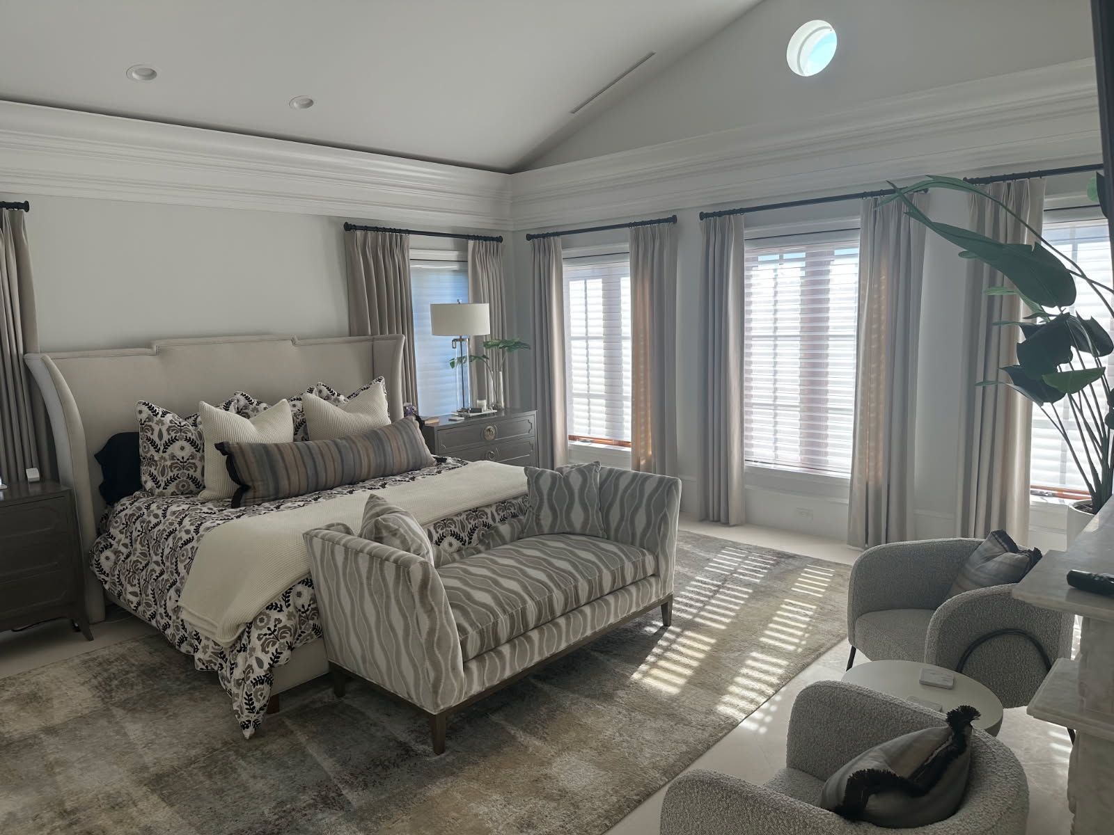 Elegant bedroom with a large bed, seating area, and natural light.
