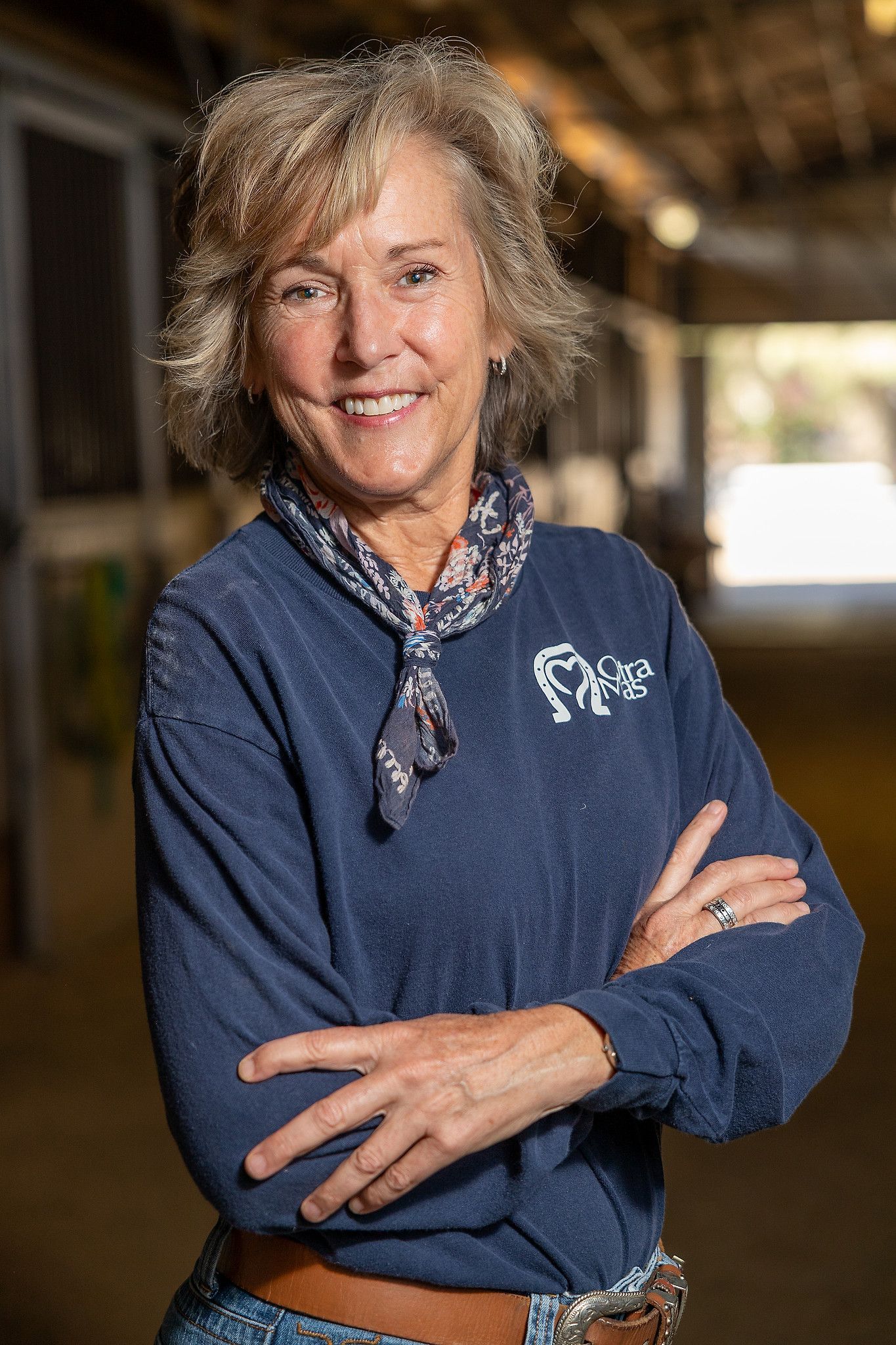 Woman with silver hair smiles next to a brown horse with white star on forehead. They stand outdoors.