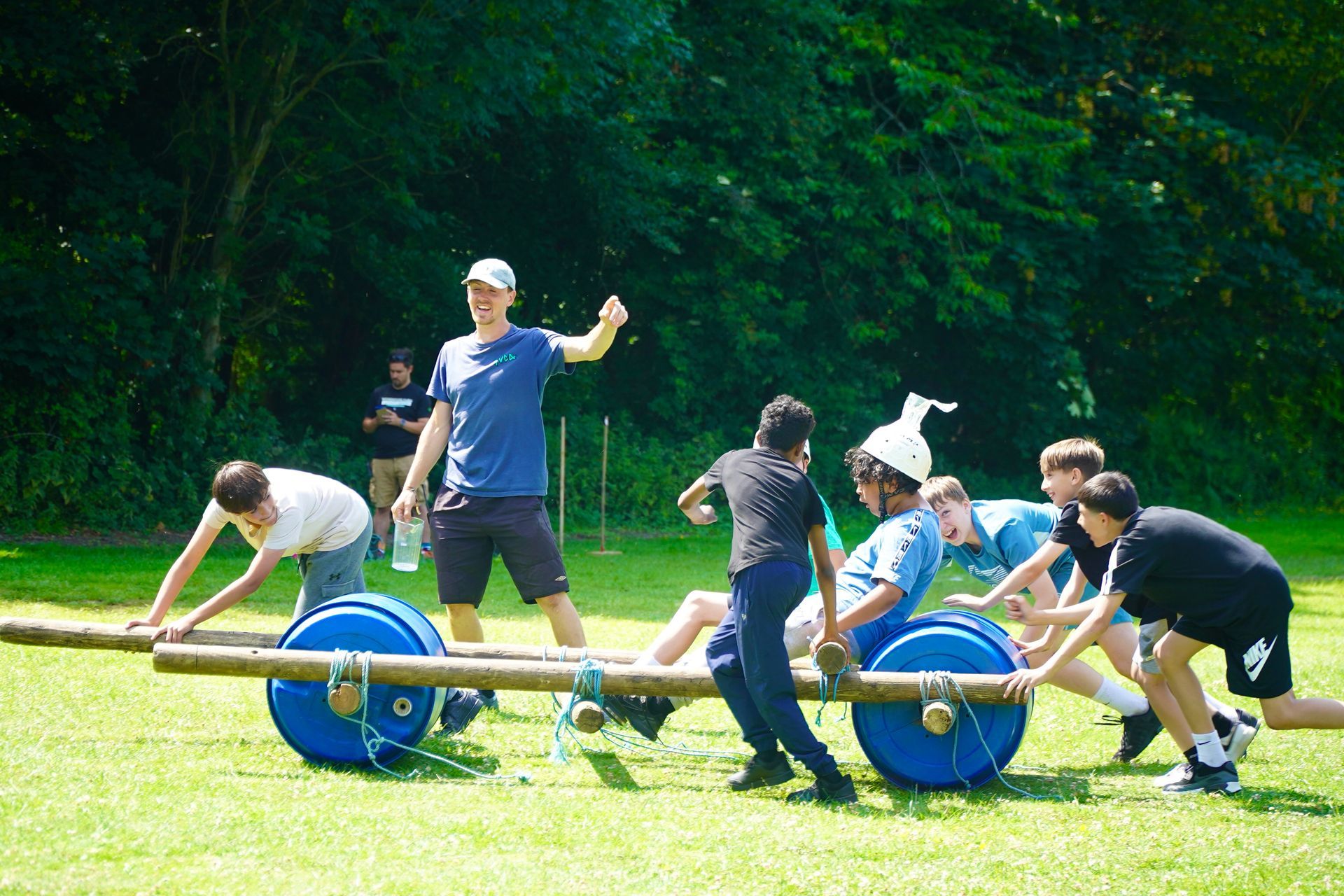People playing a game outdoors with a wooden cart and blue wheels.