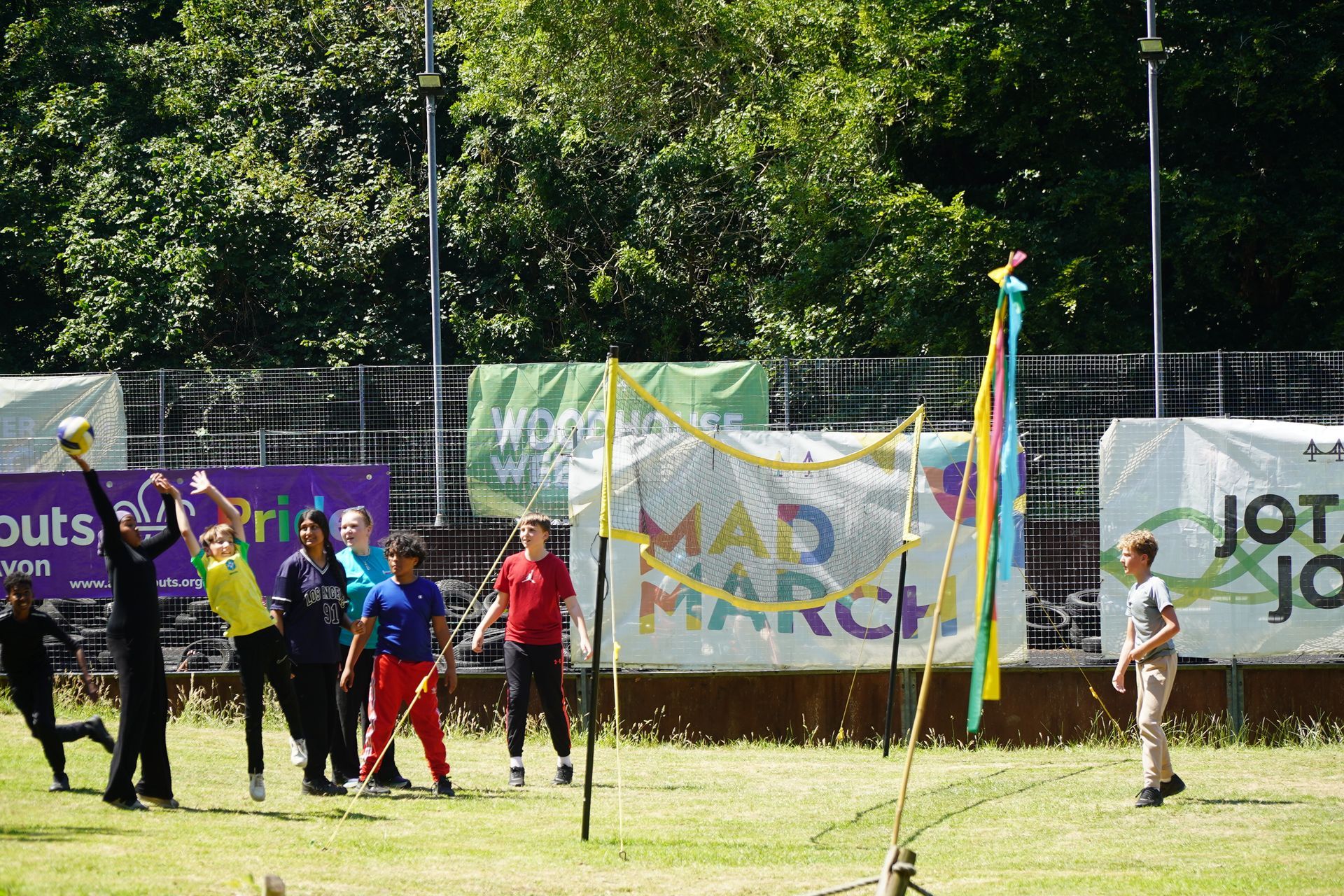 People playing volleyball outdoors with a net on a green field.