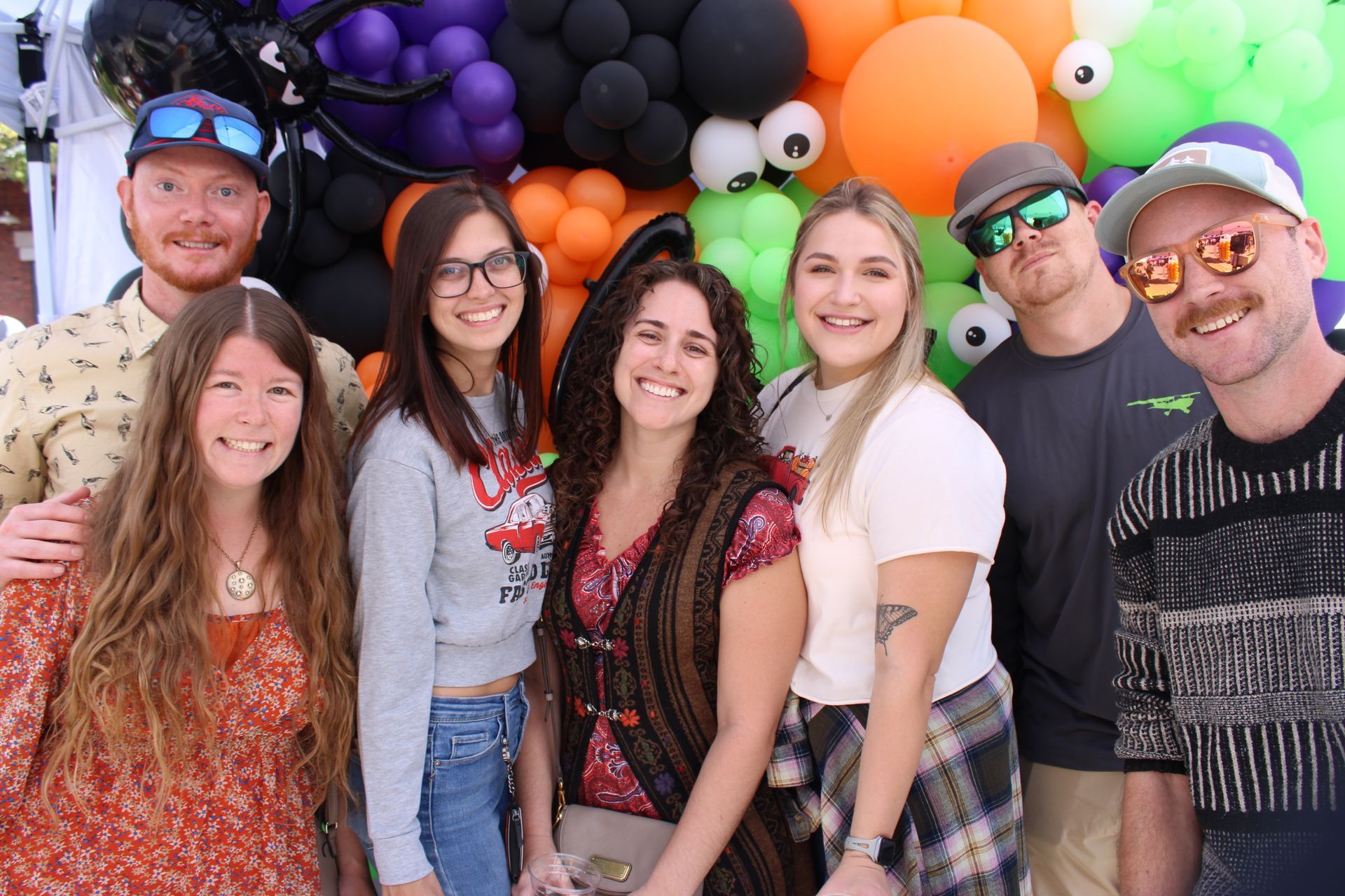 A group of people are posing for a picture in front of a wall of balloons.