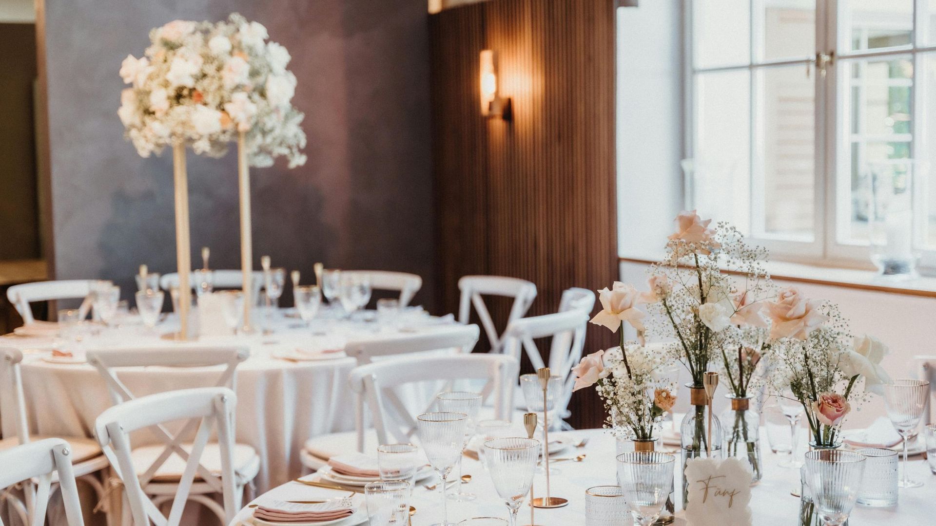 A long wooden table and chairs are set for a wedding reception.