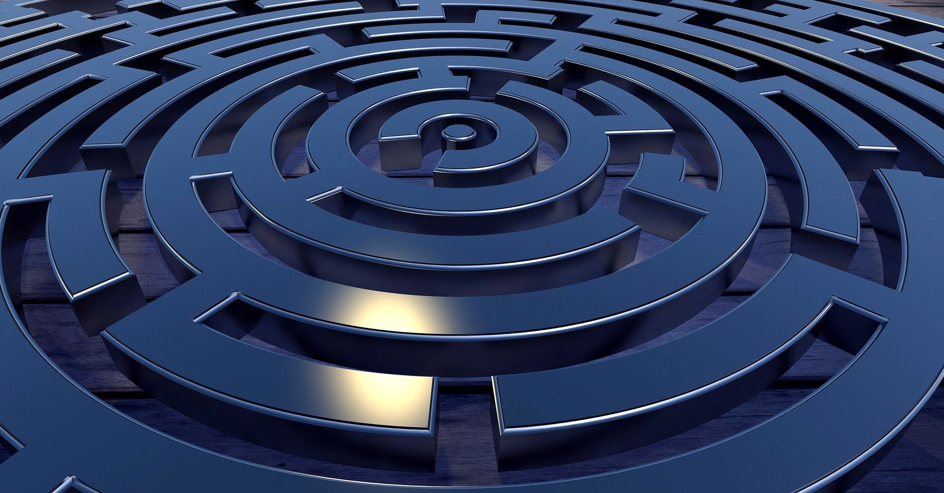 Um labirinto metálico circular com paredes concêntricas, apresentando superfícies refletoras e sombras em um tom profundo de azul.