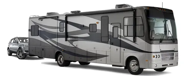 Gray and white RV towing a small silver car.