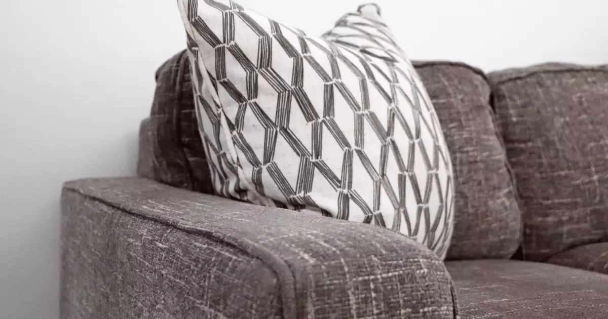 Close-up of a brown sofa with a patterned pillow, showcasing upholstery before sofa steam cleaning