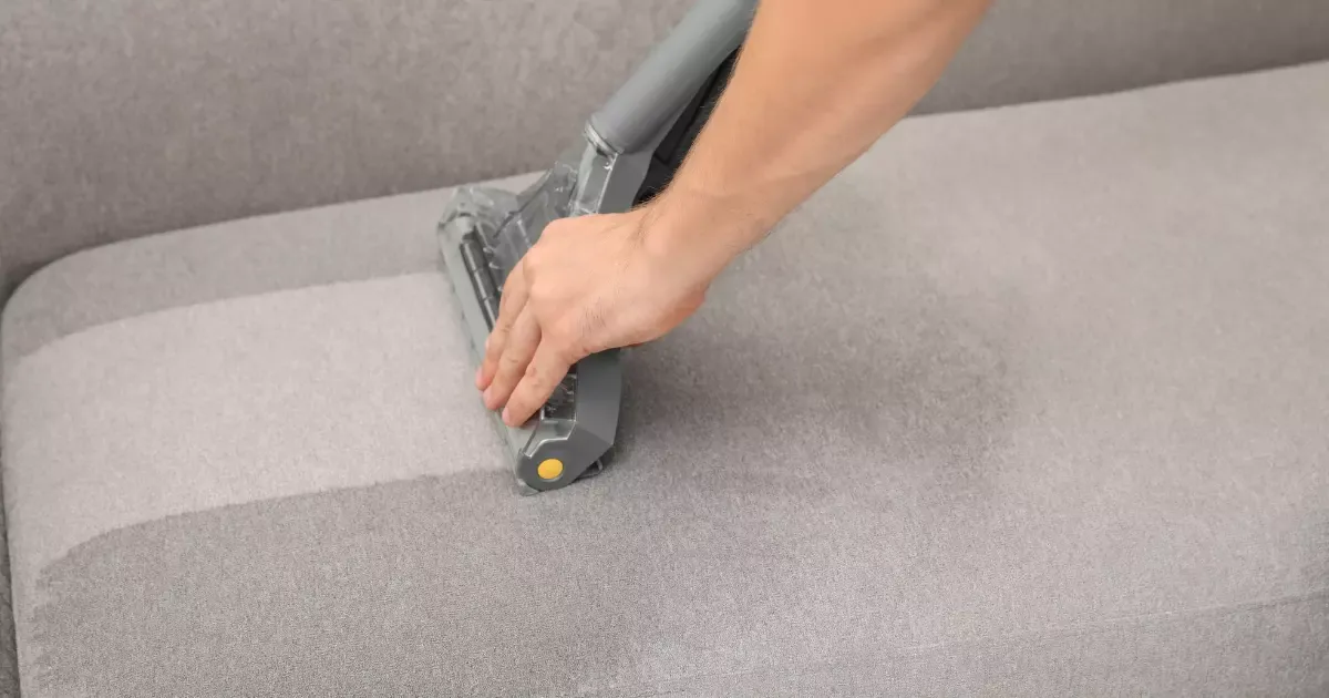 Detailed view of sofa steam cleaning process on a gray upholstered cushion using a handheld extractor