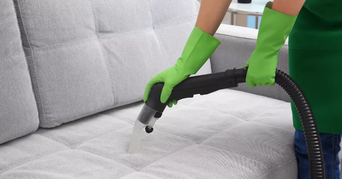 Expert using specialized equipment for detailed couch cleaning near me on a light gray sofa