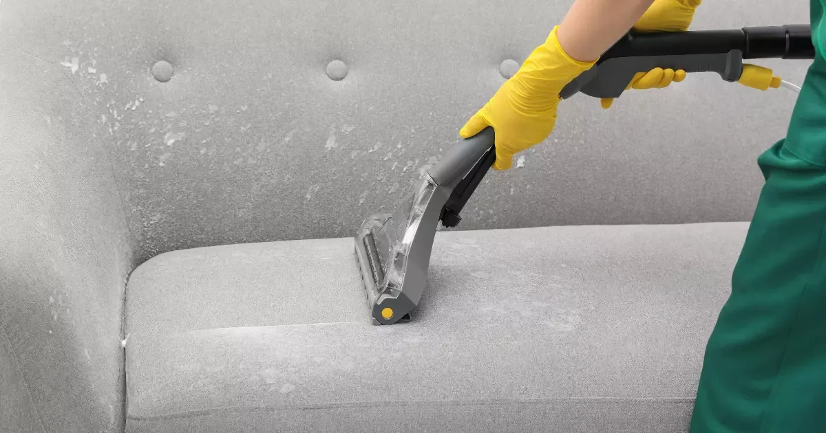 Professional deep cleaning a light gray couch with a steam cleaner, showcasing couch cleaning near me