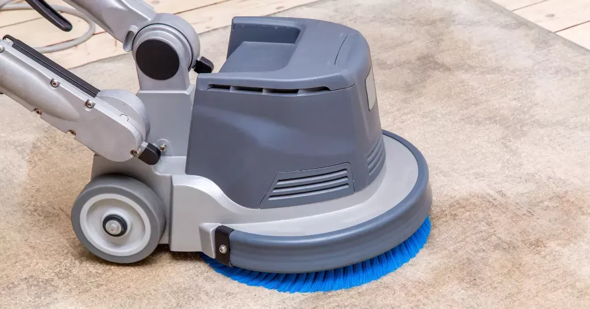 A professional rug cleaning machine scrubbing a carpet with a rotating brush