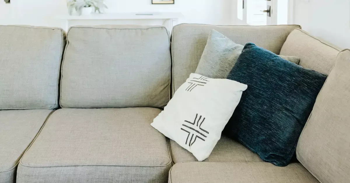 Light-colored fabric sofa with decorative pillows, ideal for professional upholstery cleaning