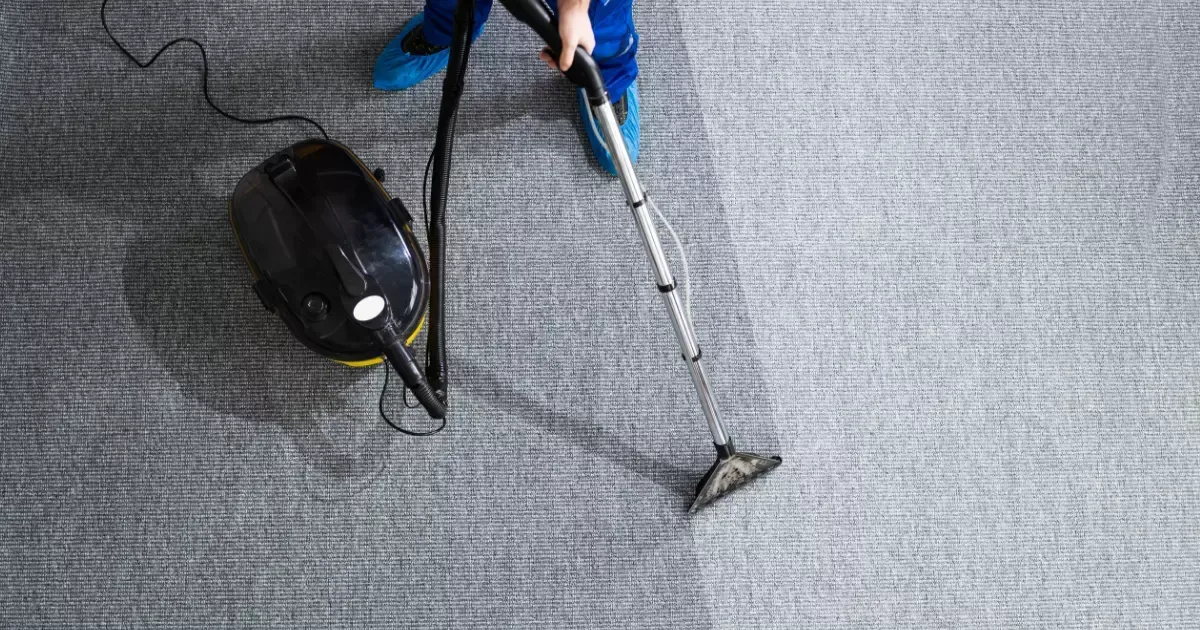 A person vacuuming carpet with a vacuum cleaner