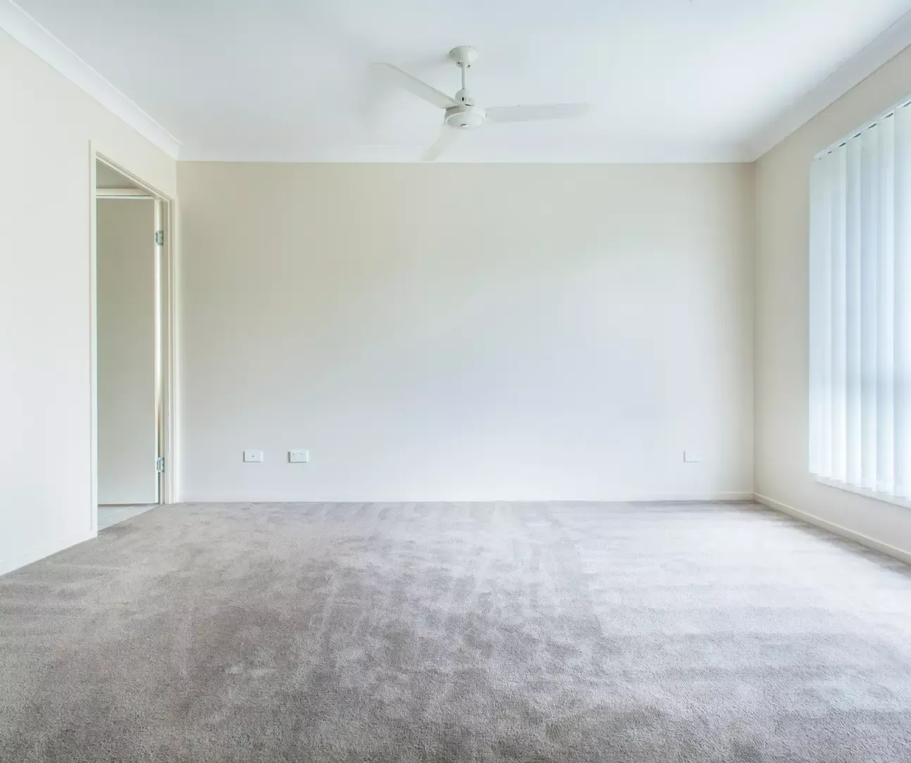 Empty room with freshly vacuumed gray carpet after professional carpet cleaning service