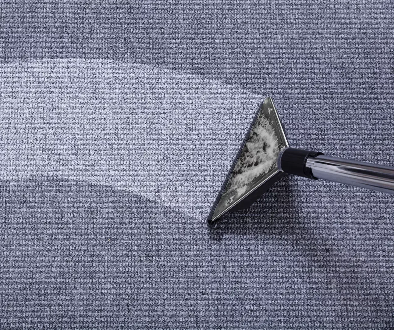 Carpet cleaning wand extracting dirt from gray carpet for a deep, professional clean