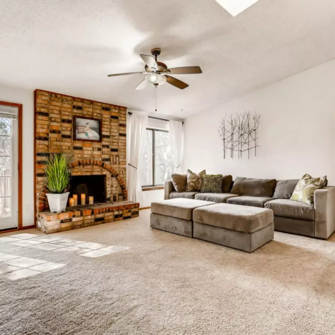 Bright living room with brick fireplace and freshly cleaned carpet after professional carpet cleaning services