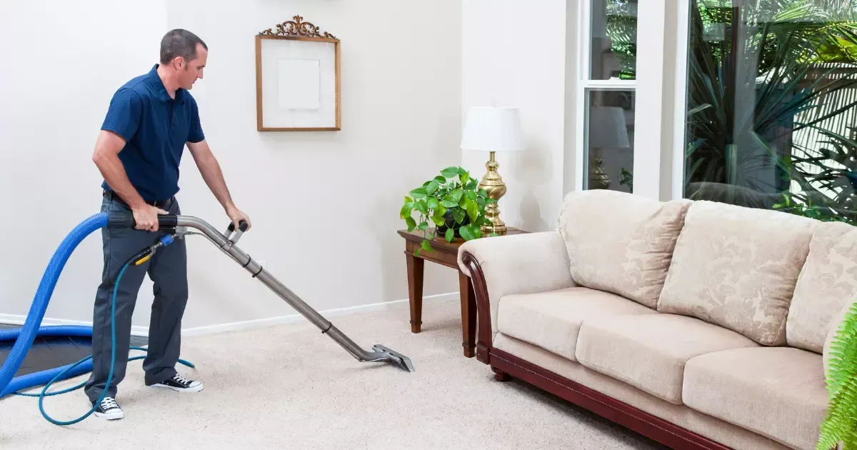 A person vacuuming the carpet in a living room