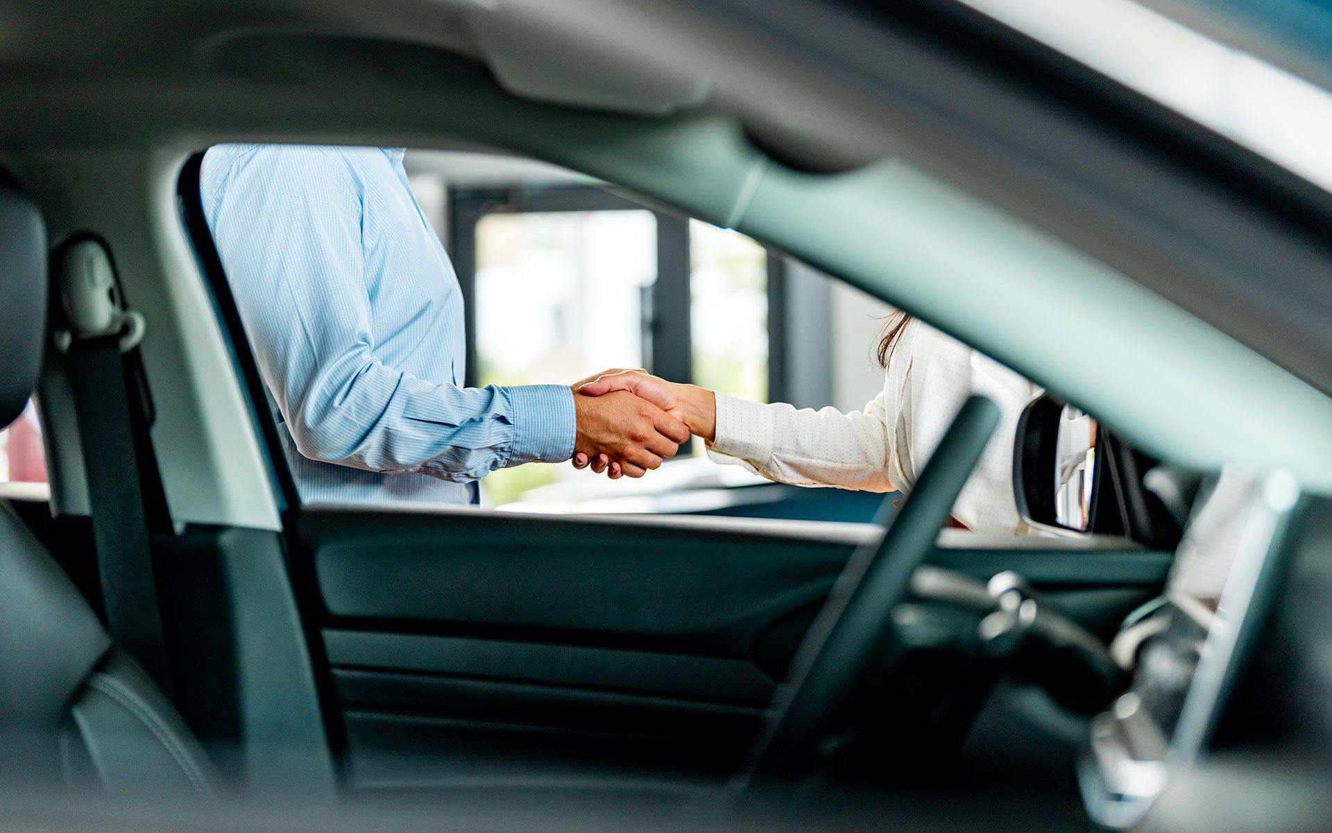 A man and a woman are shaking hands in a car.
